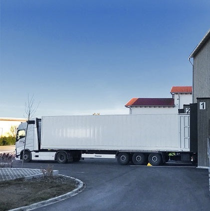 Camion avec semi-remorque blanche devant un entrepôt